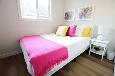 a bedroom with a white bed with a pink blanket at Downtown 3 Queen Beds, AC, Double Garage, Disney in Edmonton