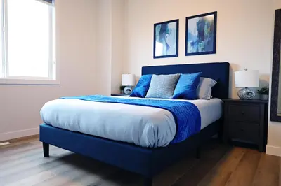 a blue bed with blue pillows in a bedroom at Downtown 3 Queen Beds, AC, Double Garage, Disney in Edmonton