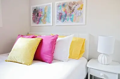 a white couch with colorful pillows on it at Downtown 3 Queen Beds, AC, Double Garage, Disney in Edmonton