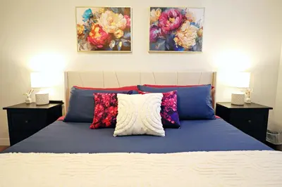 a bedroom with a bed with pillows and paintings on the wall at Downtown Suite King Beds,Long Stays,Disney+ in Edmonton