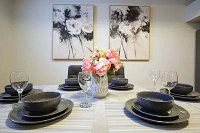 a table with plates and glasses and a vase with flowers at Downtown 5 Bedroom, AC, Rogers, Commonwealth, EXPO in Edmonton