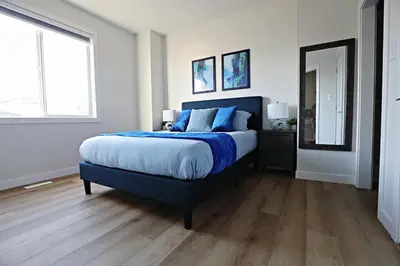 a bedroom with a large bed with blue pillows at Downtown 5 Bedroom, AC, Rogers, Commonwealth, EXPO in Edmonton