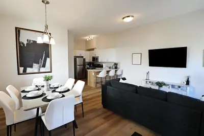 a living room with a black couch and a table and chairs at Central 3 Queen Beds, AC, Double Garage, Disney in Edmonton