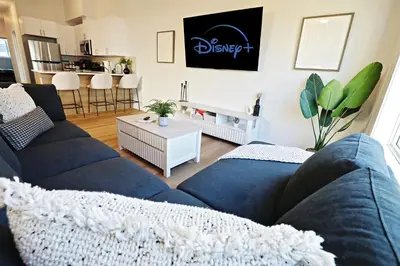 a living room with a blue couch and a table at Central 3 Queen Beds, AC, Double Garage, Disney in Edmonton