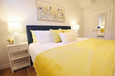 a bedroom with a large bed with a yellow blanket at Central Suite King Beds,Long Stays,Disney+ in Edmonton