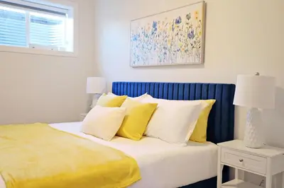 a bedroom with a bed with yellow and white pillows at Central 5 Bedroom, AC, Rogers, Commonwealth, EXPO in Edmonton
