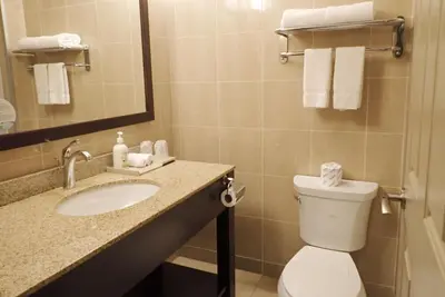 a bathroom with a toilet and a sink and a mirror at Days Inn & Suites by Wyndham Fort Saskatchewan in Fort Saskatchewan