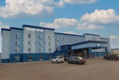 a large building with cars parked in a parking lot at Days Inn & Suites by Wyndham Fort Saskatchewan in Fort Saskatchewan