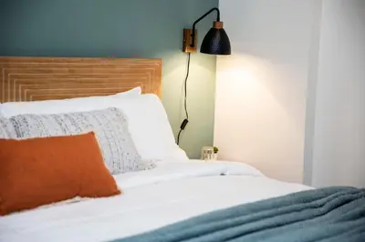 a bed with white sheets and an orange pillow at The Stellar Condo - Cozy 2 Bedroom with Hot Tub in Revelstoke