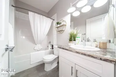 a white bathroom with a sink and a toilet at Boho Suite - Long Stays - King Bed - Fireplace & WiFi in Edmonton