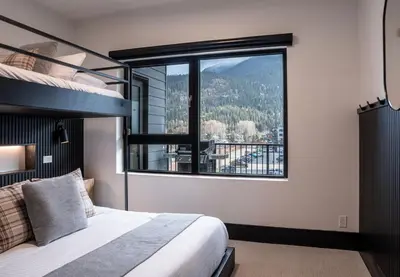 a bedroom with a bed and a large window at Altitude Adjustment by Revelstoke Vacations in Revelstoke