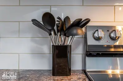 a black vase filled with utensils next to a stove at BoHo Chic Suite - Long Stays - Fireplace - Garage in Edmonton