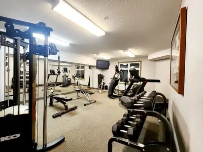 a gym with several treadmills and machines in a room at W118 NEW! Central Canmore- Light Industrial Hotel Room in Canmore