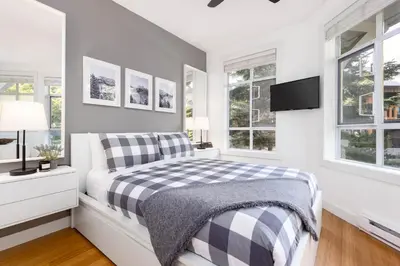 a white bedroom with a black and white bed and windows at 2BR in Granite Court, Village Location, Gas Fireplace, Mudroom, Secure Parking in Whistler