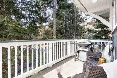 a porch with chairs and a grill on it at 2BR in Granite Court, Village Location, Gas Fireplace, Mudroom, Secure Parking in Whistler