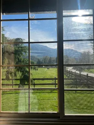 a window with a view of a field and a fence at Farm House - L&S Farms in Chilliwack