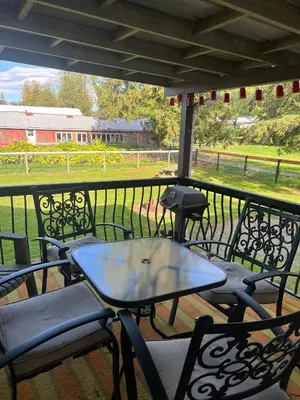 a table and chairs on a porch with a view of a field at Farm House - L&S Farms in Chilliwack