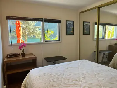 a bedroom with a bed and two windows at Waterfront, Mountainview House in Castlegar in Castlegar