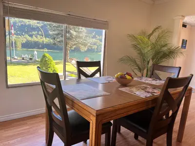 a dining room table with chairs and a large window at Waterfront, Mountainview House in Castlegar in Castlegar