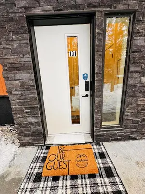 a door mat in front of a door with a be out guest sign at Ski In Ski Out Private Hot Tub in Panorama