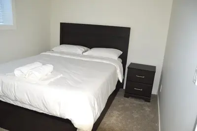 a bedroom with a large bed and a night stand at Secondary Suite, Separate Entrance NW Calgary in Calgary