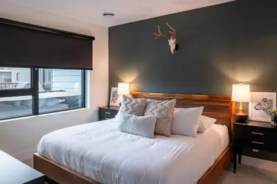 a bedroom with a bed with white sheets and a window at Hemlock Hangout by Revelstoke Vacations in Revelstoke