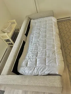 a bed with white sheets on it in a room at Homelike & cozy suite in Langley