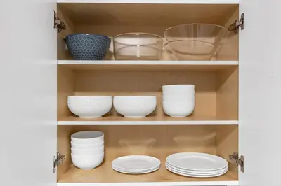 a shelf with bowls and plates in a cabinet at Pristine 3 Beds 2 Washroom Guest Suite in Surrey