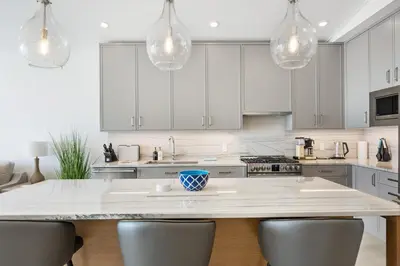 a kitchen with white cabinets and a large island with chairs at Beachfront Luxury Suite #15 at THE BEACH HOUSE in Campbell River