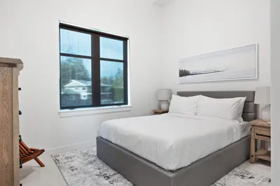 a white bedroom with a bed and a window at Beachfront Luxury Suite #15 at THE BEACH HOUSE in Campbell River