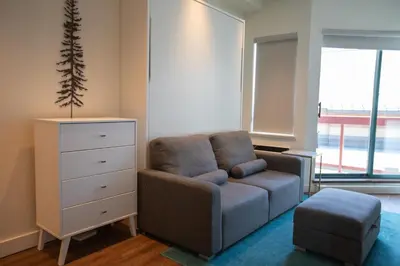 a living room with a couch and a dresser at Studio in Market Pavilion, Private Balcony, Common Hot Tub, Epic Village Location, Parking in Whistler