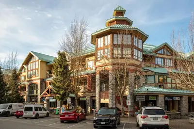 a tall building with cars parked in front of it at Studio in Market Pavilion, Private Balcony, Common Hot Tub, Epic Village Location, Parking in Whistler