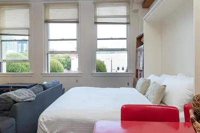 a bedroom with a bed and a couch and windows at Be Vogue In Old Town Victoria in Victoria