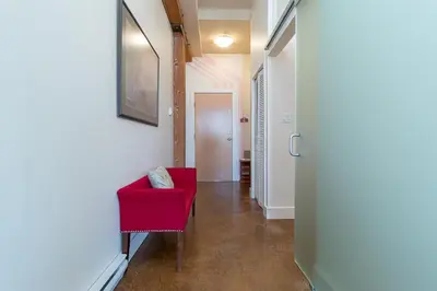 a hallway with a red chair and a door at Be Vogue In Old Town Victoria in Victoria