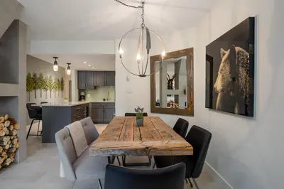 a dining room and kitchen with a wooden table and chairs at 3BR and Den in Gleneagle, Wood Burning Fireplace, Heated Flooring, Secure Parking in Whistler