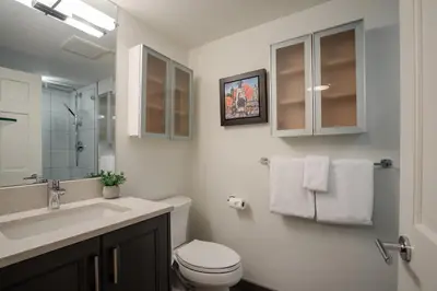 a white bathroom with a toilet and a sink at 3BR and Den in Gleneagle, Wood Burning Fireplace, Heated Flooring, Secure Parking in Whistler