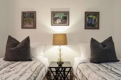 a bedroom with two beds and a lamp at 3BR and Den in Gleneagle, Wood Burning Fireplace, Heated Flooring, Secure Parking in Whistler