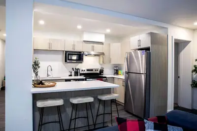 a kitchen with a stainless steel refrigerator and bar stools at Absolutely Revy - Ground Level Condo in Revelstoke in Revelstoke
