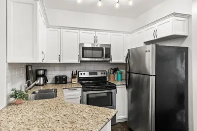 a kitchen with white cabinets and a stainless steel refrigerator at Stunning Mountain Views - Pool&HotTub - King Bed - BBQ in Canmore