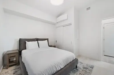 a white bedroom with a large bed with white sheets at Beachfront Luxury Suite #21 at THE BEACH HOUSE in Campbell River