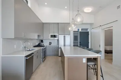 a kitchen with white cabinets and a kitchen island with chairs at Beachfront Luxury Suite #21 at THE BEACH HOUSE in Campbell River