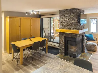 a dining room with a table and a fireplace at 2 Bedroom and Wall Bed Mountain Getaway Ski In Ski Out Condo with Hot Pools Sleeps 8 in Panorama