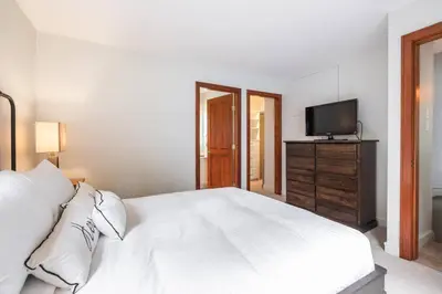 a bedroom with a white bed and a television at Treeline by Outpost Whistler in Whistler