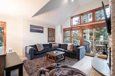 a living room with a couch and a table at Treeline by Outpost Whistler in Whistler