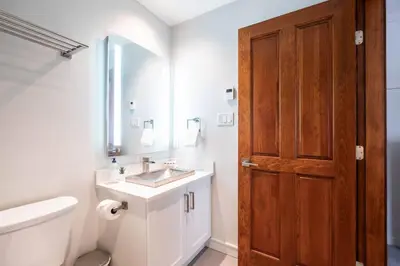 a bathroom with a sink and a toilet and a wooden door at Treeline by Outpost Whistler in Whistler
