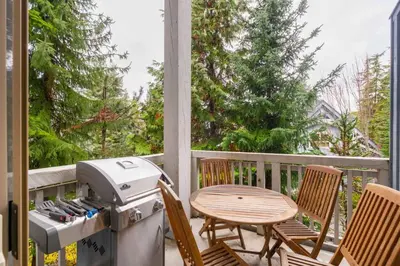 a patio with a grill and two chairs and a table at Treeline by Outpost Whistler in Whistler