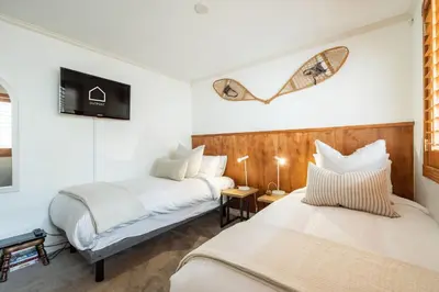 two beds in a room with a tv on the wall at Foxglove by Outpost Whistler in Whistler