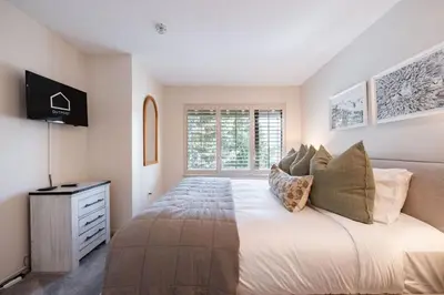 a bedroom with a bed and a dresser and a window at Foxglove by Outpost Whistler in Whistler