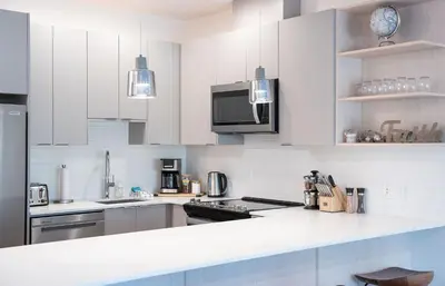 a kitchen with white cabinets and stainless steel appliances at Mountainside Revival by Revelstoke Vacations in Revelstoke