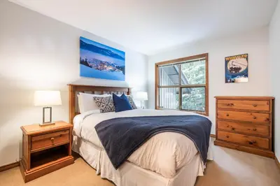 a bedroom with a large bed and a window at Blackcomb Greens by Outpost Whistler in Whistler